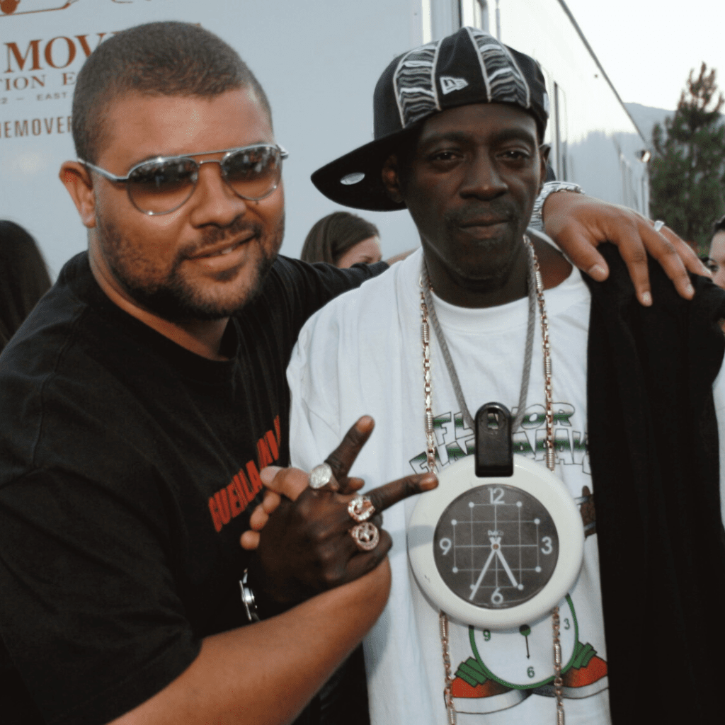 Andre Ramone posing backstage with Flavor Flav at Rock the Bells in 2007, standing arm in arm as Flavor Flav makes a peace sign
