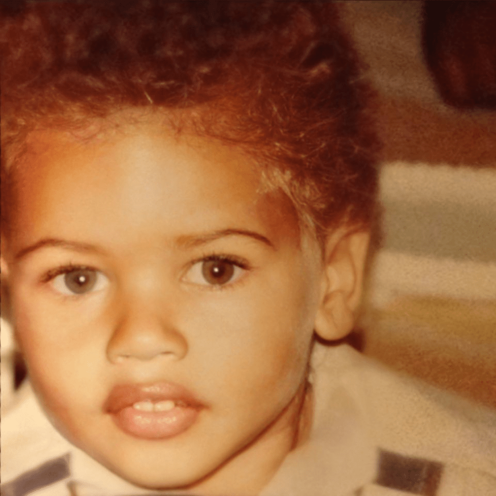 Restored childhood portrait of Andre Ramone as a toddler, facing the camera with a small afro, wearing a collared shirt and overalls